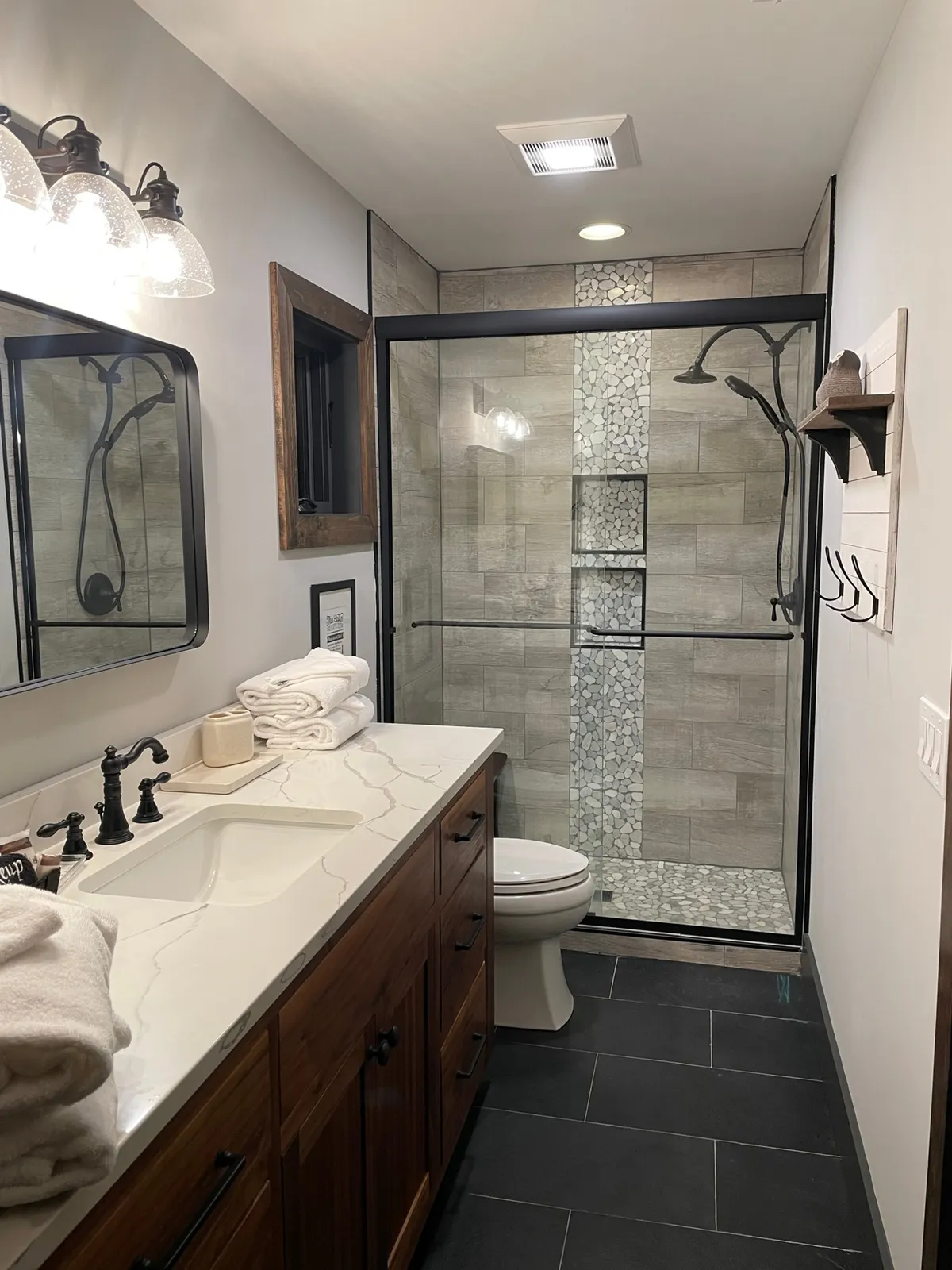 A serene bathroom featuring a double-sink vanity, modern glass shower, and wood accents. Soft lighting and clean lines evoke a spa-like atmosphere, ideal for personal privacy and rejuvenation.