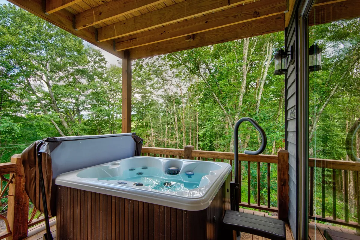 A serene hot tub set on a wooden deck, surrounded by mature trees and forest views. The setting offers privacy and immersion in nature, perfect for unwinding after wine tastings or a day of exploration.